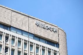 Exterior view and logo of Meiji University Surugadai Campus.